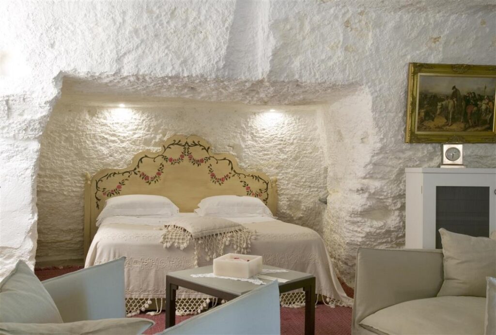 camera di colore bianco fatta di roccia con letto bianco d'epoca e piccoli divani